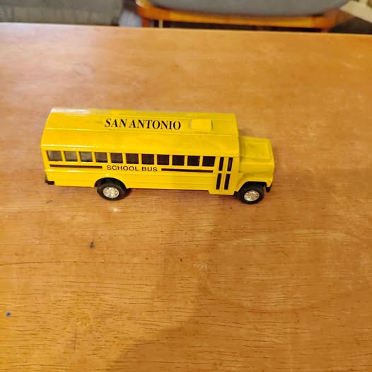 Yellow diecast school bus with San Antonio lettering and black wheels, side view