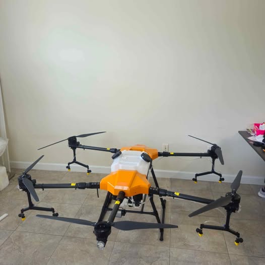 Multi-rotor agricultural drone sprayer with orange body and black frame