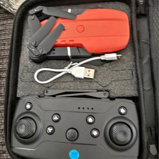 Black drone remote controller with dual thumb sticks and buttons, with USB cable.