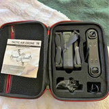 Air drone kit in open hard case with folded drone and spare parts compartments