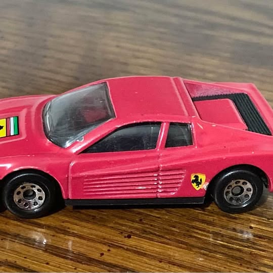 Red diecast sports car model with black grille, Ferrari shield, and black wheels
