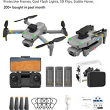 Gray quadcopter drone with camera and prop guards, shown with controller and accessories