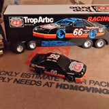 Diecast NASCAR trailer truck with race car, black and orange, blue wheels