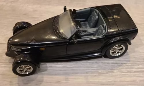 Dark diecast sports car with open cockpit and silver wheels, 1:24 scale