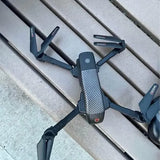 Foldable quadcopter drone with gray body and blue arms, top camera module visible