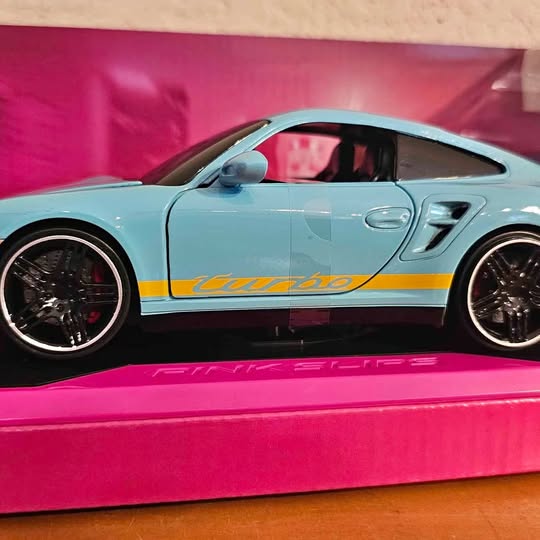 Light blue diecast sports car model with black wheels and yellow racing stripe, 1:24 scale