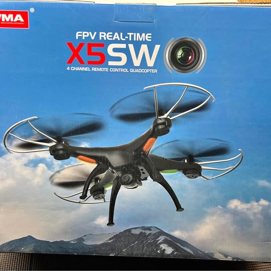Black RC quadcopter drone with FPV camera and four propellers, orange accents