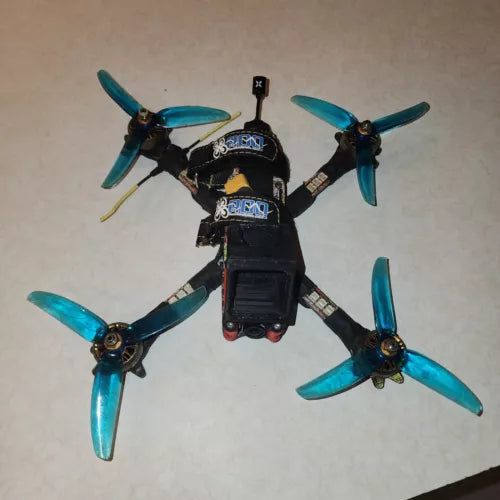FPV freestyle racing drone with four blue propellers, black frame