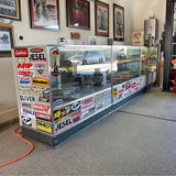 Glass display case with diecast cars and stacked original-style boxes