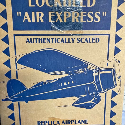 Diecast replica airplane, blue with silver details, side view on packaging