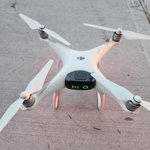 DJI Phantom 4 drone with white body and four propellers, front status lights lit