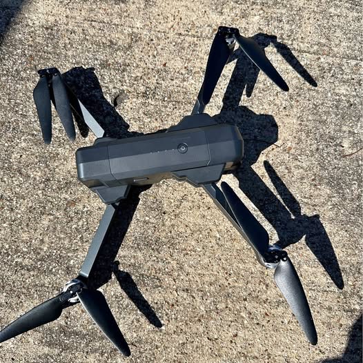 Foldable quadcopter drone with four propeller arms extended, black body