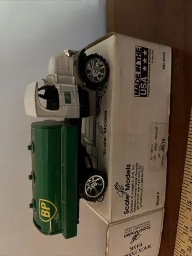 Green and white die-cast oil tanker truck coin bank with BP logo and wheels