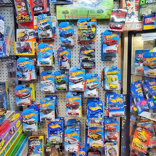 Hot Wheels diecast slot car packages on pegboard, assorted models