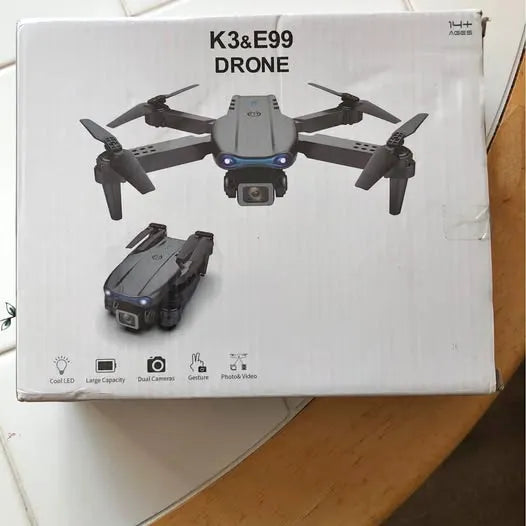 Compact quadcopter drone with front camera and four rotors on retail box