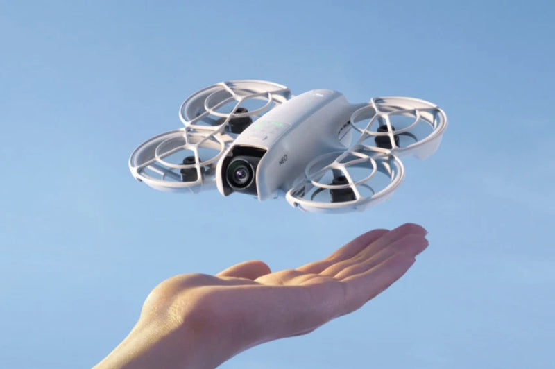 DJI Neo mini drone with four propellers hovering above a hand
