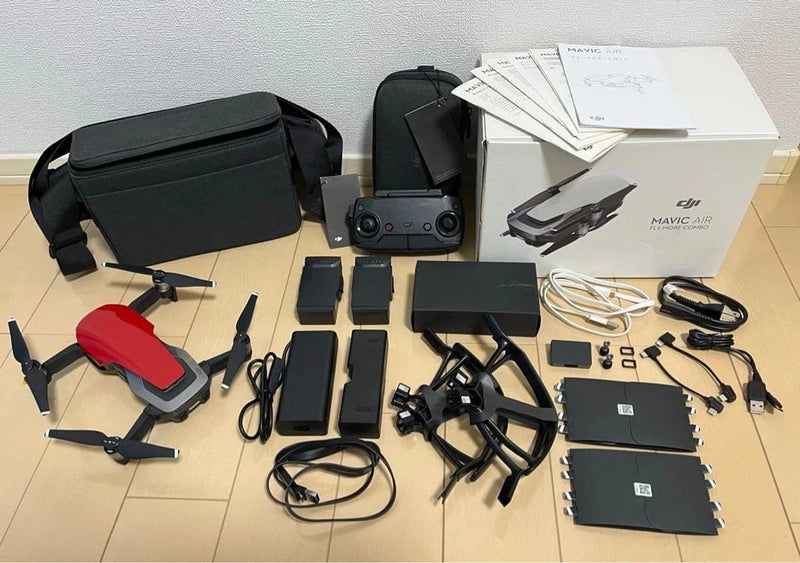 Red DJI Mavic Air drone kit with remote, batteries, charger cables, and carrying case