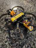 Black and yellow FPV quadcopter drone with protective ducts, front-top view