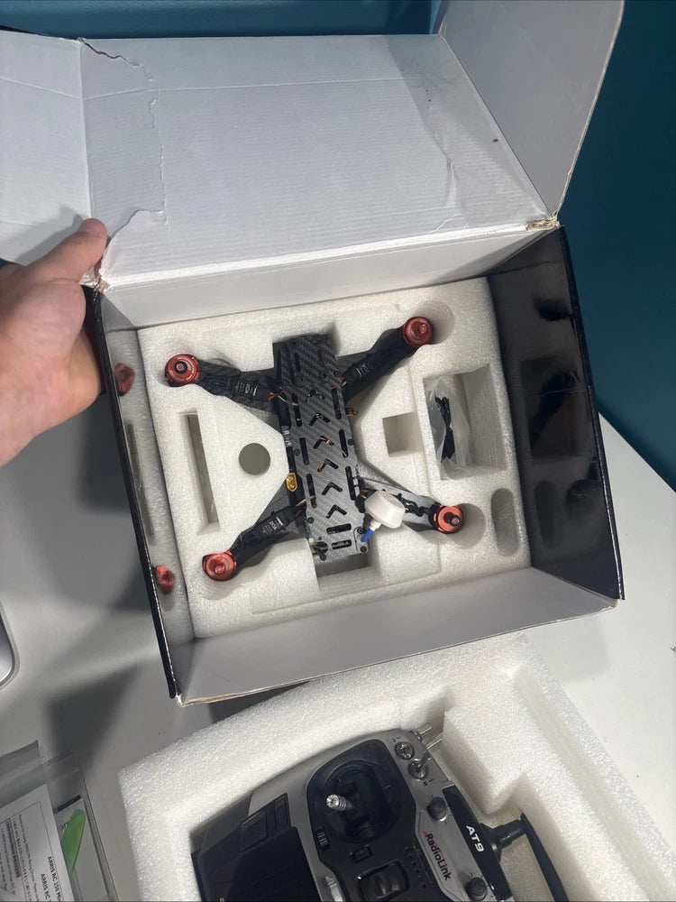 Black quadcopter mini drone with red arms in open molded foam box