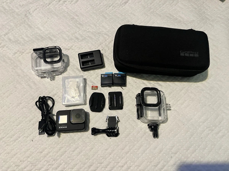 Black action camera with protective case and waterproof housing, plus charging and mounts