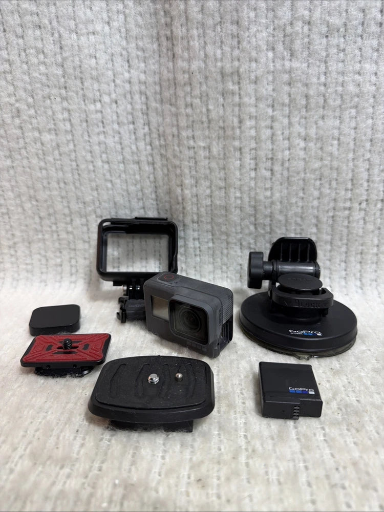 Black action camera with housing and mounting accessories, including suction mount and mounts