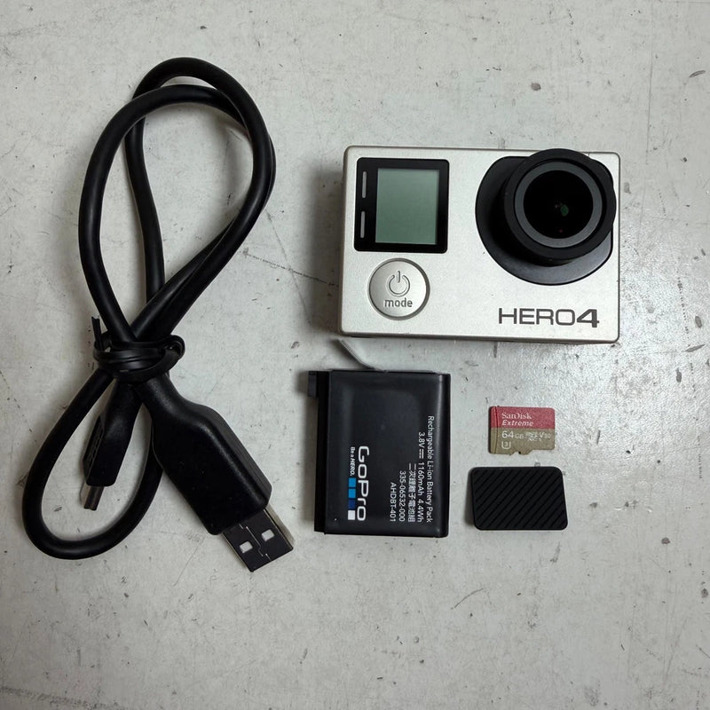 Silver action camera with touchscreen, lens, battery, USB cable, and microSD card
