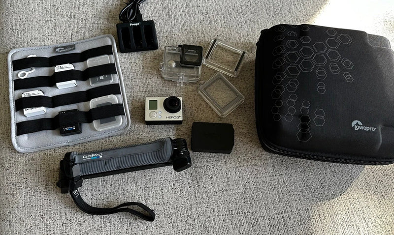 Silver action camera with accessories, carrying case, mounts, batteries, and storage cards
