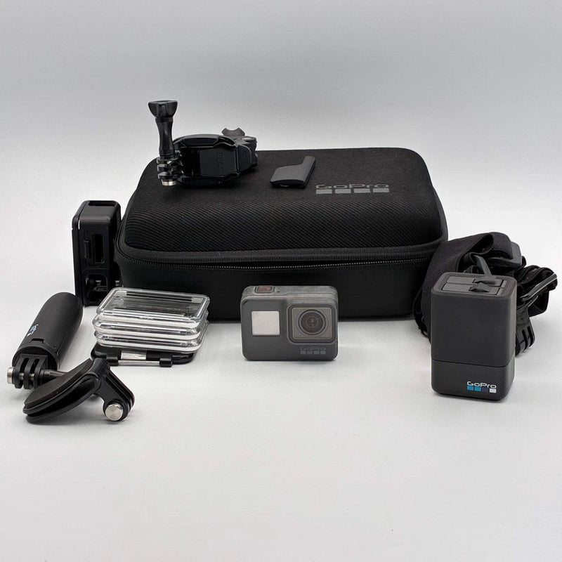Gray action camera with waterproof case and mounting accessories, plus black storage case.