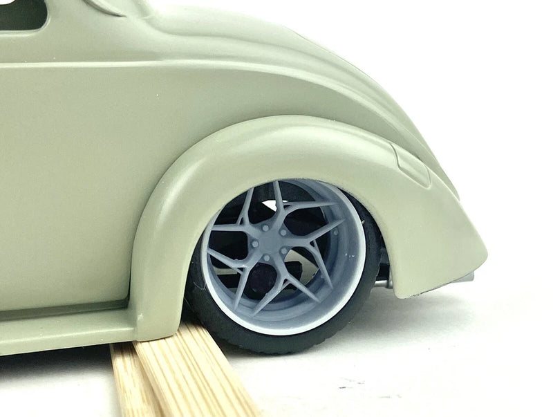 Model car wheel and tire with multi-spoke silver rim and black tire, close-up