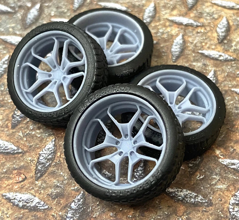 Set of four resin model car wheels with black tires and light gray spoke rims