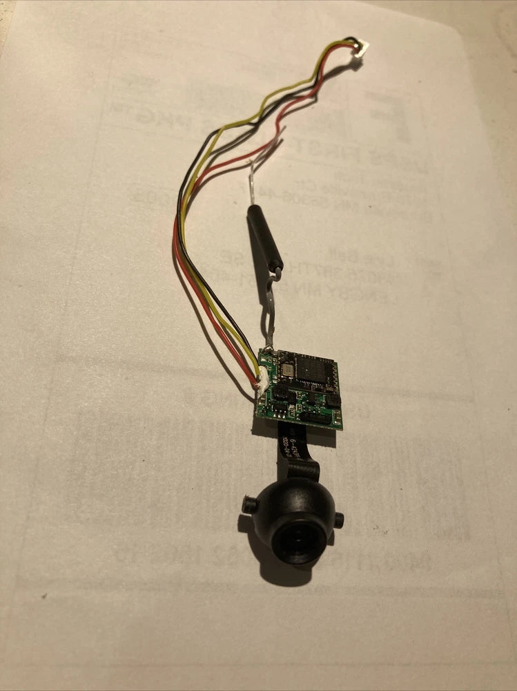 Drone camera module with circuit board, black lens, and colored wiring