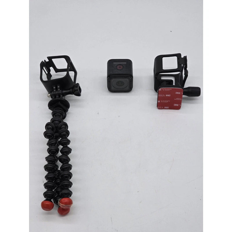 Action camera accessory lot with mini tripod legs, compact camera, and mounting case