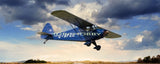 Dark RC airplane model with blue stripe flying, tail and propeller visible