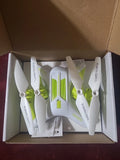 White foldable drone with green propellers, packaged in open box
