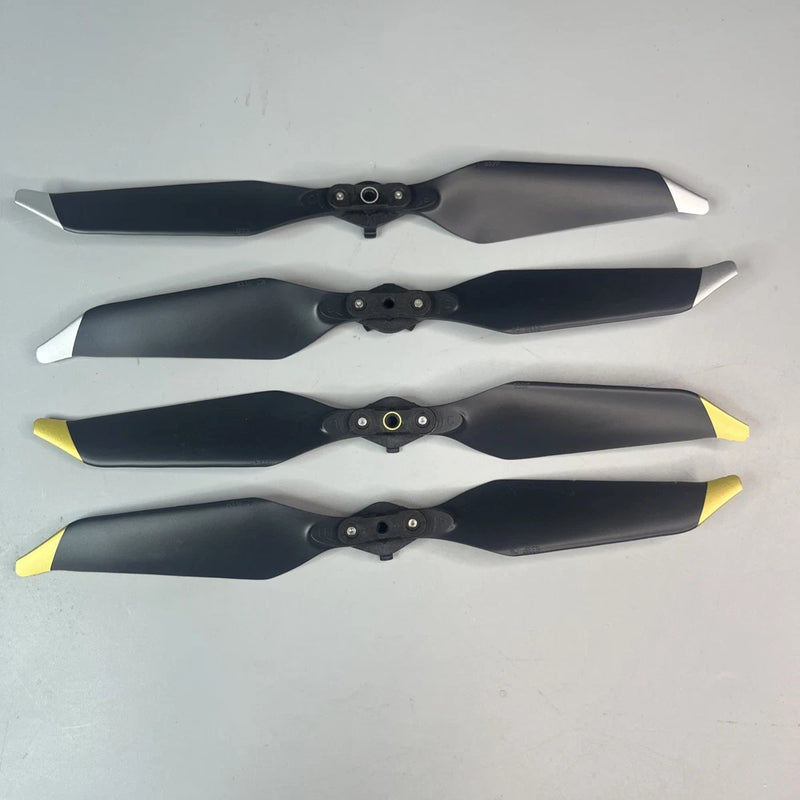 Set of four drone propellers with quick-release hubs; dark blades with white/yellow tips