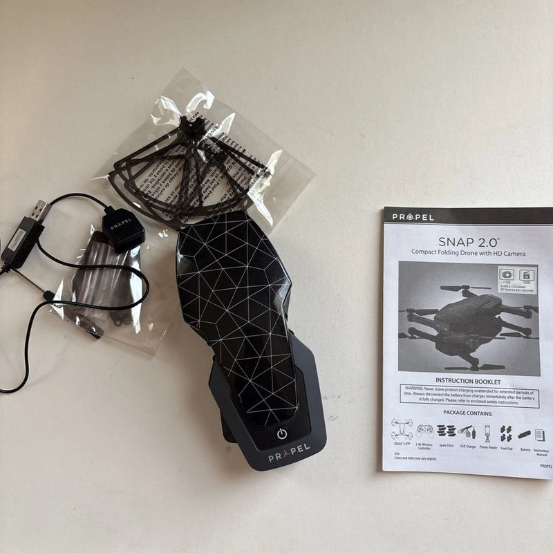 Compact folding drone with HD camera, folded black body and instruction booklet