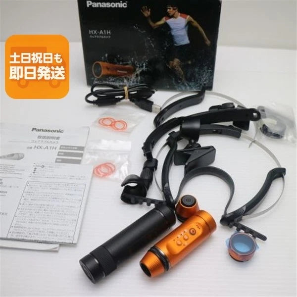 Orange Panasonic action camera with black mounts, lens cover, and accessories set
