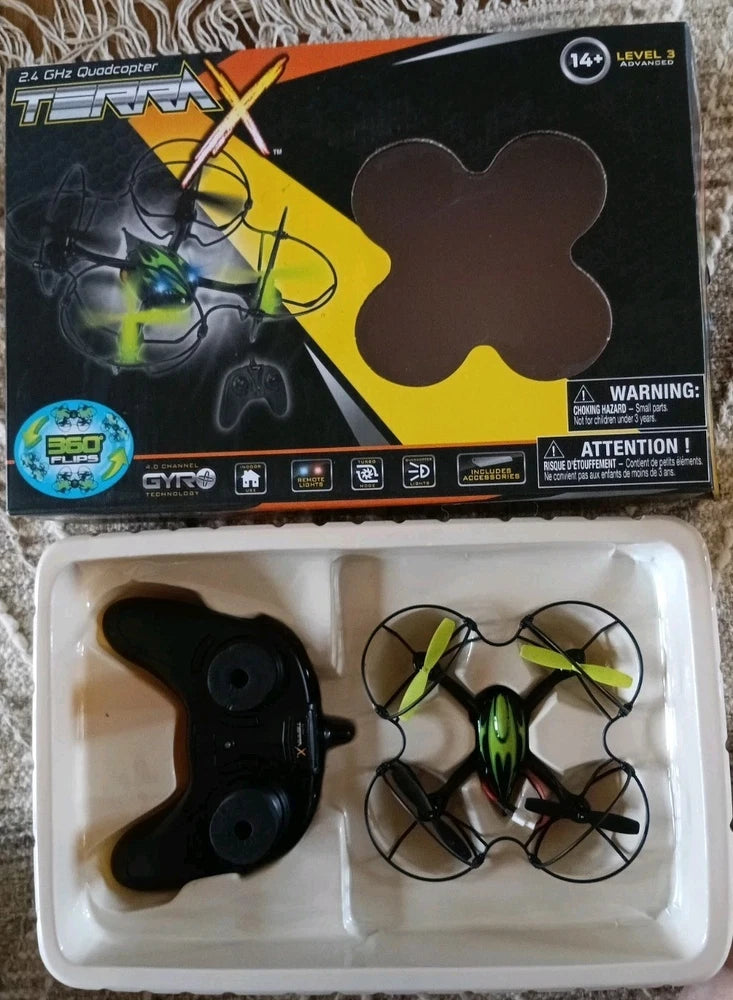 Quadcopter drone with green-lit propellers and controller, in retail box tray