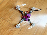 Small purple FPV quadcopter drone with four propellers and exposed electronics