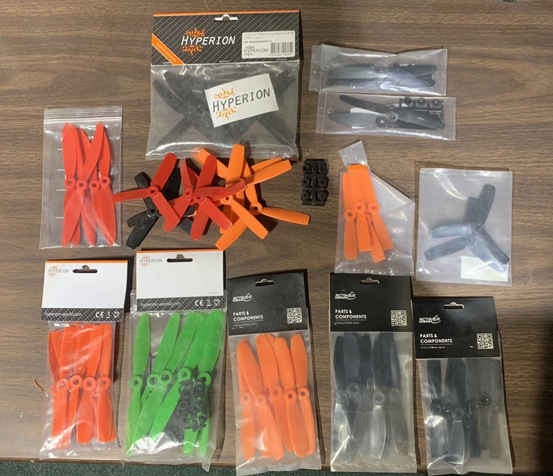 FPV drone propeller set, orange and green blades with spare mounting parts in packs