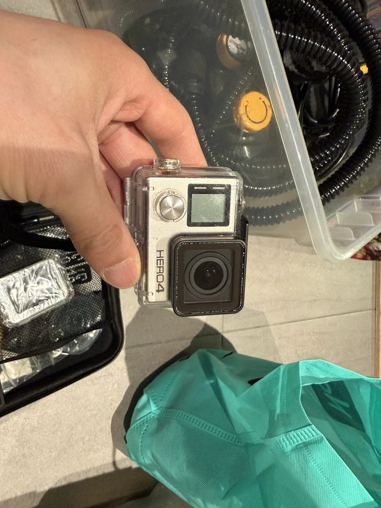 Silver GoPro Hero 4 action camera with front lens and touchscreen, held in hand