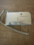 Silver HP PhotoSmart E317 compact digital camera with 5.0 megapixels and wrist strap