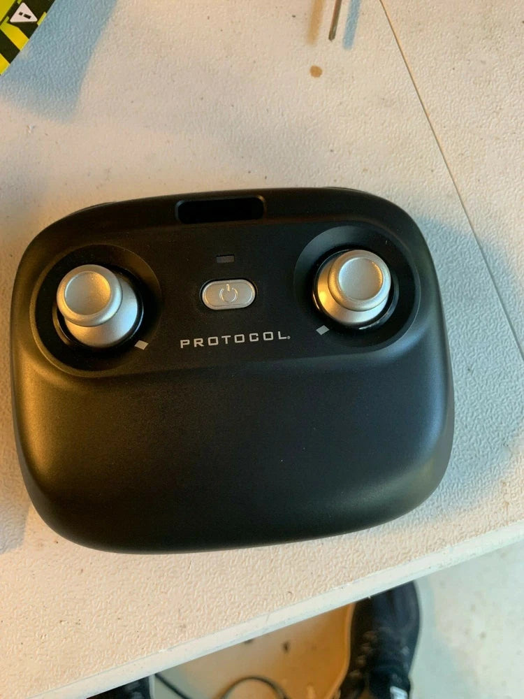 Protocol Director remote controller, black device with two circular knobs and central PROTOCOL text.