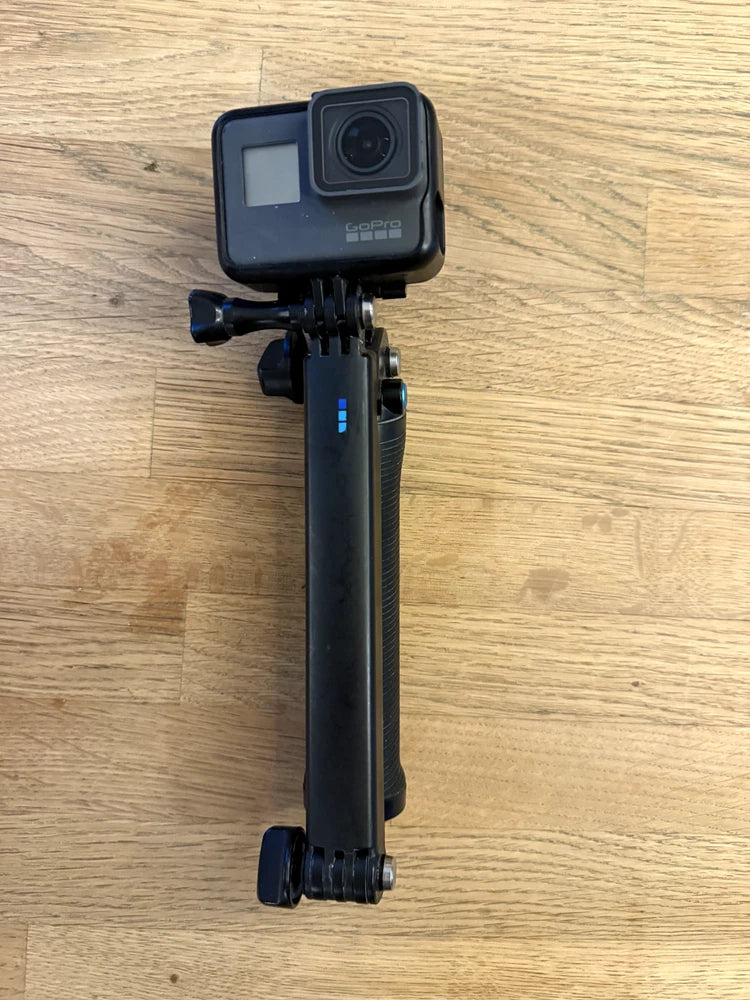 Black action camera mounted on a tripod-style selfie stick, GoPro Hero 5 Black Edition