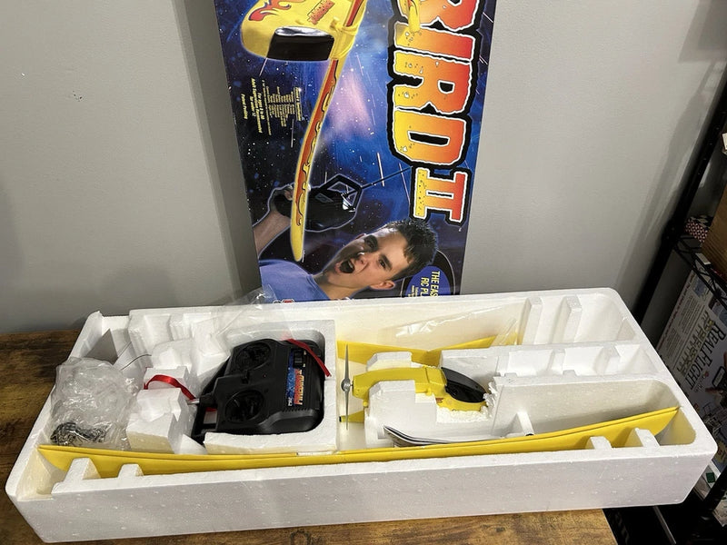 Vintage RC airplane kit with yellow-and-black model and controller parts in tray