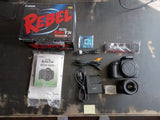 Canon EOS Rebel T3i digital SLR camera kit with black body, lens, cables, manuals.