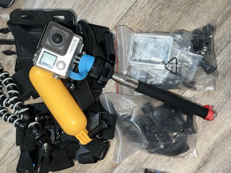 GoPro HERO4 action camera kit with yellow grip, straps, mounts, and spare parts