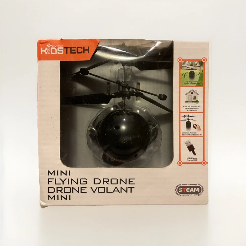 Mini flying drone in retail box, black quadcopter with four rotors and prop guards.