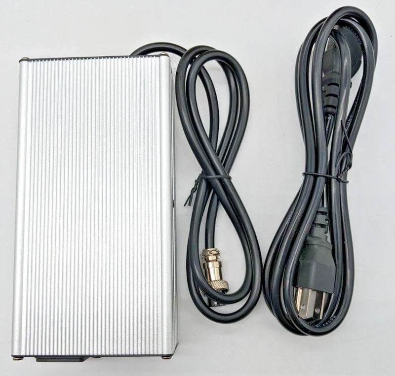 Compact battery charger with ribbed metal casing and black power cables with plug