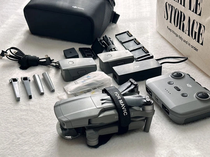 Grey foldable drone with remote controller, batteries, and storage case